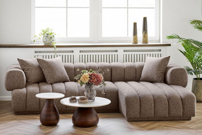 Bouclé hoekbank in een lichte woonkamer met houten bijzettafels